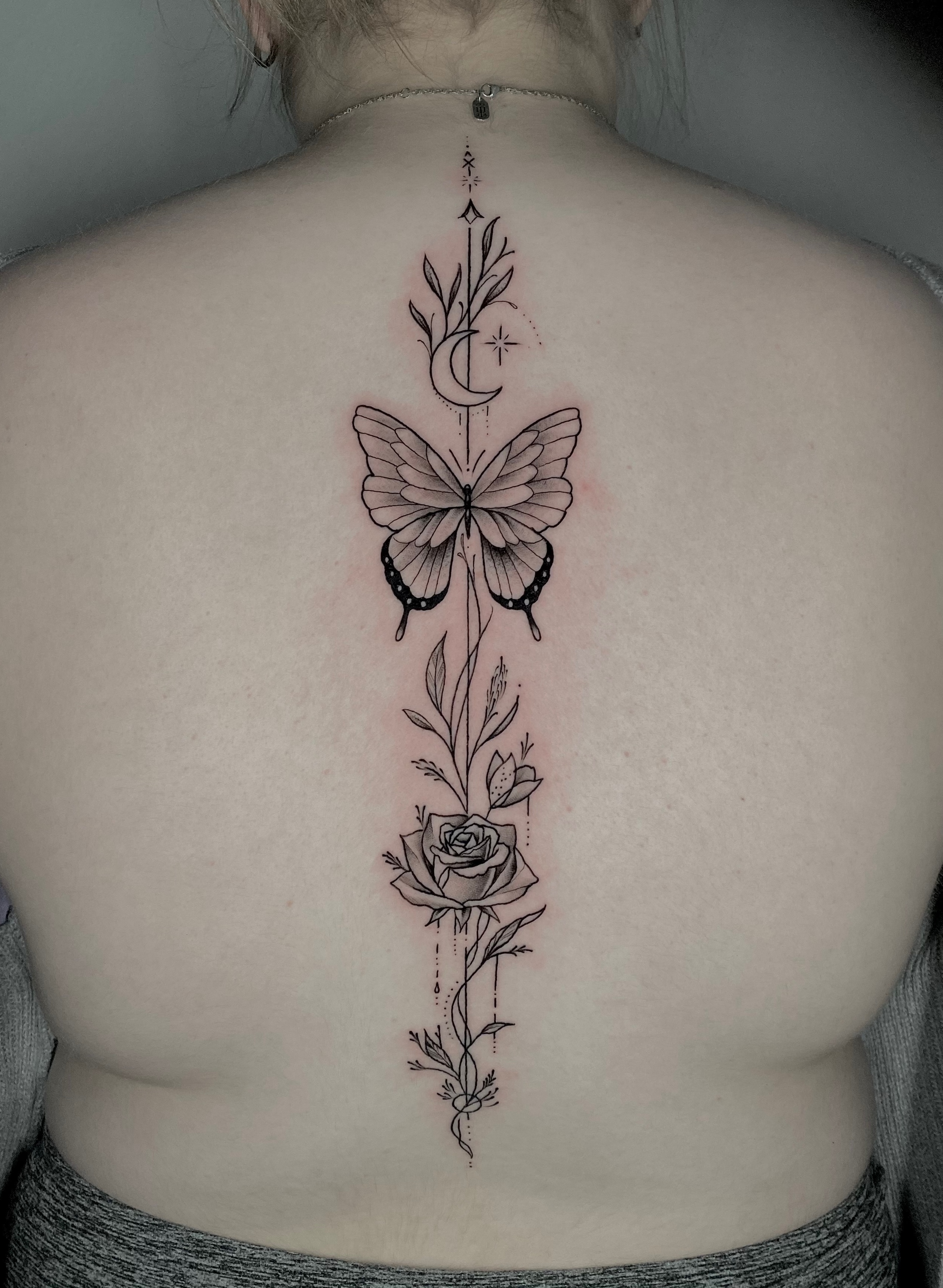 Fine Line Black Butterfly, Flower tattoo on the Spine by Remy at Platinum Tattoos & Piercings, San Antonio TX